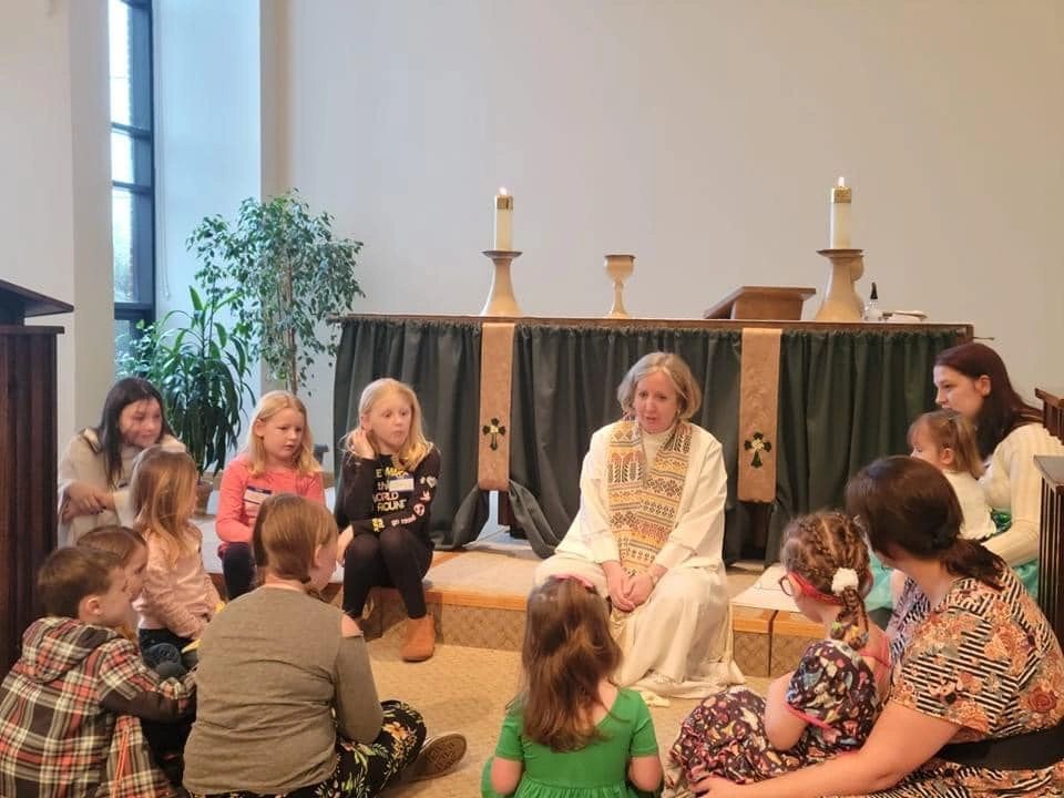 Pastor Darcy leading a children's sermon at the front of the sanctuary