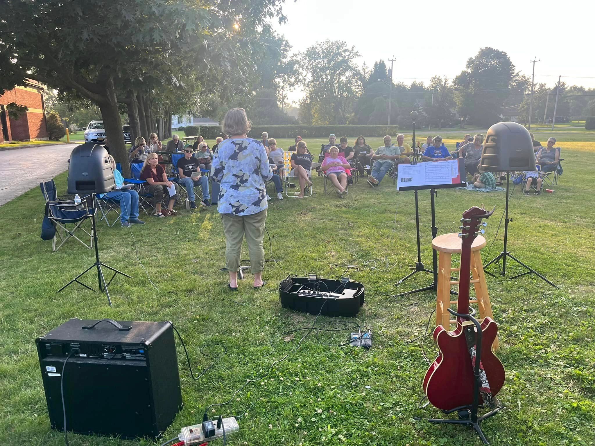 Outdoor worship on the church lawn with guitar and small congregation