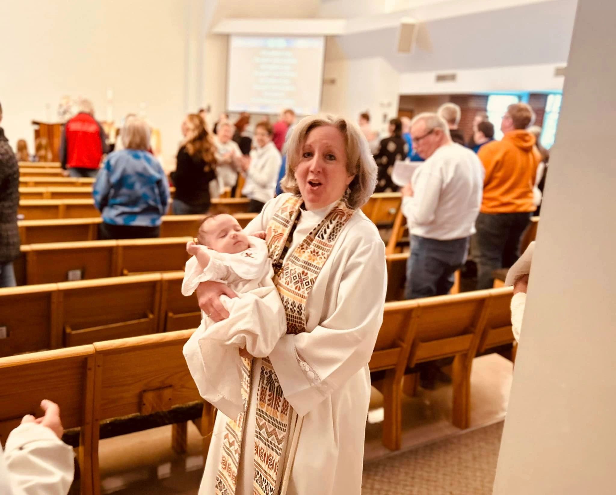 Pastor Darcy holding a child during baptism at Lord of Life
